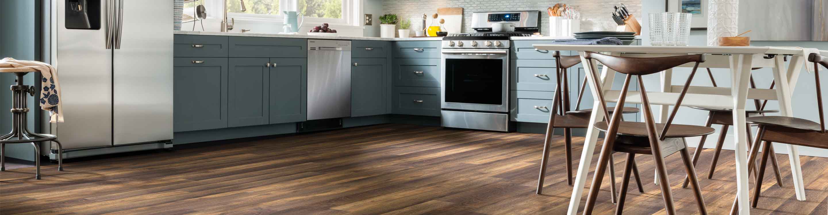 dark wood-look vinyl flooring in contemporary kitchen with white table, wood chairs and blue cabinetry